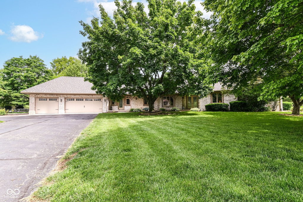 7220 Normandy Way, Indianapolis, IN 46278 - obstructed view of property featuring driveway, a garage, a front yard, and brick siding