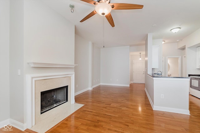 355 E Ohio St Unit 209, Indianapolis, IN 46204 - unfurnished living room featuring light wood-style flooring, ceiling fan, a fireplace, a sink, and baseboards