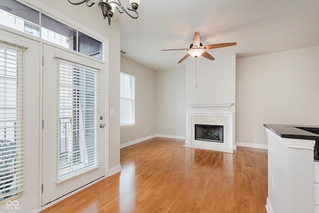 355 E Ohio St Unit 209, Indianapolis, IN 46204 - unfurnished living room with light wood-type flooring, a chandelier, a ceiling fan, and a fireplace with flush hearth