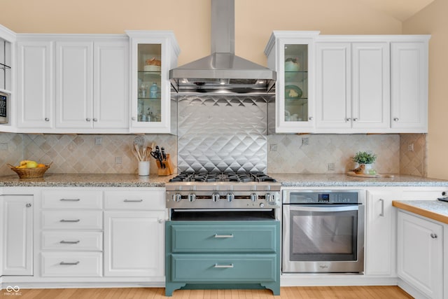 103 Gettysburg, Coatesville, IN 46121 - kitchen featuring appliances with stainless steel finishes, wall chimney exhaust hood, white cabinets, and lofted ceiling