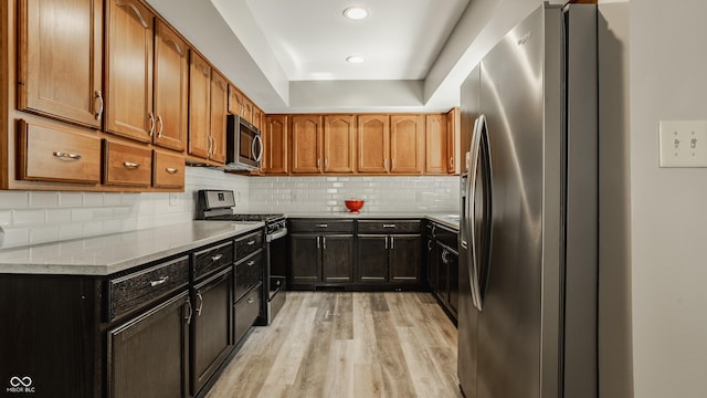 4428 Edinburgh Pt, Indianapolis, IN 46228 - kitchen featuring appliances with stainless steel finishes, light wood-style floors, light stone countertops, backsplash, and a tray ceiling