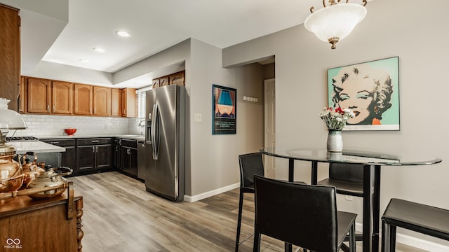 4428 Edinburgh Pt, Indianapolis, IN 46228 - kitchen featuring stainless steel fridge, light wood-style floors, decorative backsplash, baseboards, and light countertops