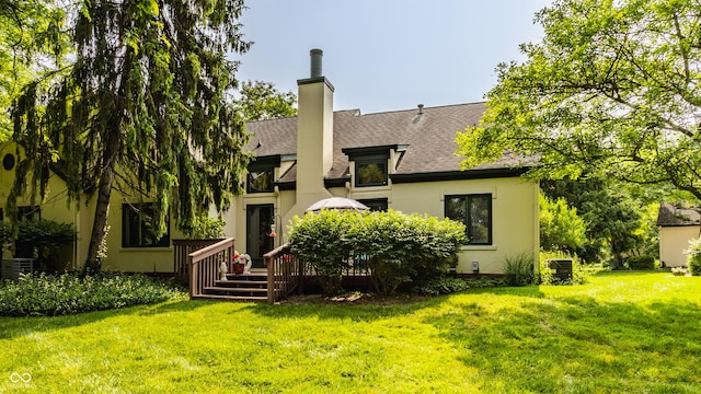 4428 Edinburgh Pt, Indianapolis, IN 46228 - rear view of property featuring a shingled roof, a wooden deck, a lawn, stucco siding, and a chimney