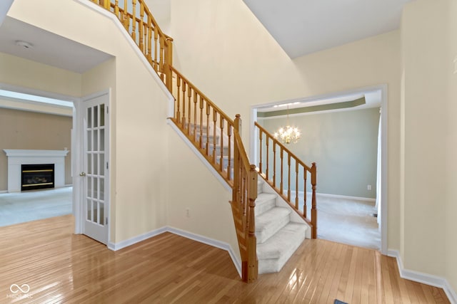 11036 Ravenna Way, Indianapolis, IN 46236 - staircase with a chandelier, wood-type flooring, baseboards, and a glass covered fireplace