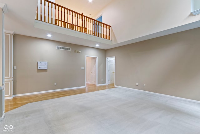 11036 Ravenna Way, Indianapolis, IN 46236 - unfurnished living room featuring a towering ceiling, baseboards, recessed lighting, carpet floors, and wood finished floors