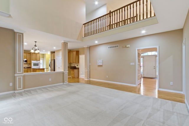 11036 Ravenna Way, Indianapolis, IN 46236 - unfurnished living room with light colored carpet, a chandelier, baseboards, ornate columns, and recessed lighting