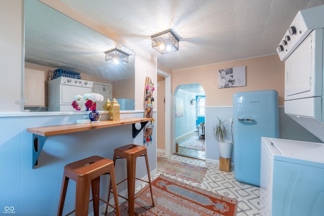 1101 S Rogers St, Bloomington, IN 47403 - kitchen featuring estacked washer and dryer, arched walkways, a kitchen breakfast bar, and baseboards