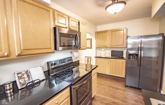 5024 N Kenwood Ave, Indianapolis, IN 46208 - kitchen featuring appliances with stainless steel finishes, light brown cabinetry, dark countertops, wood finished floors, and arched walkways