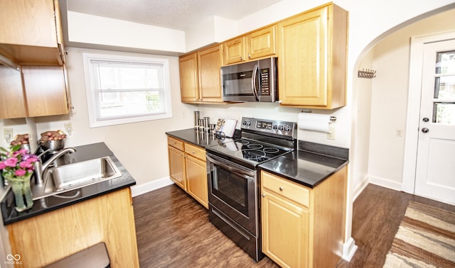 5024 N Kenwood Ave, Indianapolis, IN 46208 - kitchen with stainless steel appliances, dark countertops, arched walkways, dark wood finished floors, and light brown cabinets