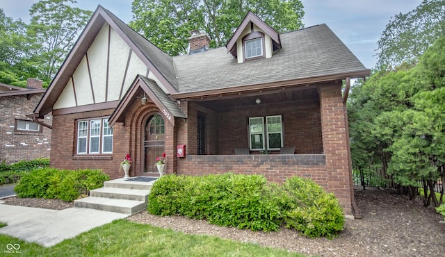 5024 N Kenwood Ave, Indianapolis, IN 46208 - view of front of house with brick siding, a chimney, a shingled roof, and stucco siding