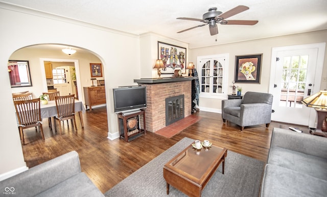 5024 N Kenwood Ave, Indianapolis, IN 46208 - living room with arched walkways, a ceiling fan, a fireplace, dark wood-type flooring, and ornamental molding