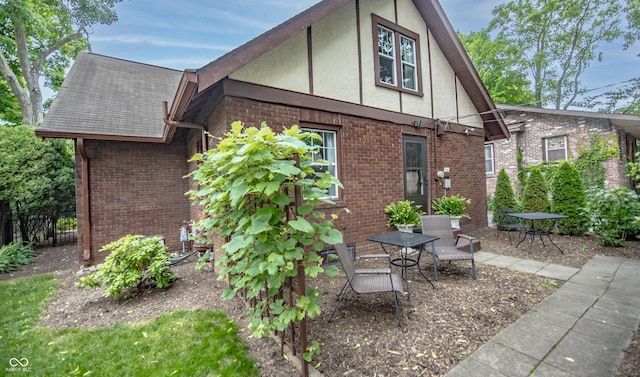 5024 N Kenwood Ave, Indianapolis, IN 46208 - view of home's exterior with stucco siding, brick siding, a patio area, and a shingled roof