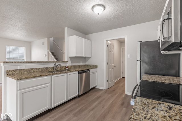 2270 Collins Way, Greenfield, IN 46140 - kitchen with appliances with stainless steel finishes, a textured ceiling, light wood-style flooring, white cabinets, and stone counters
