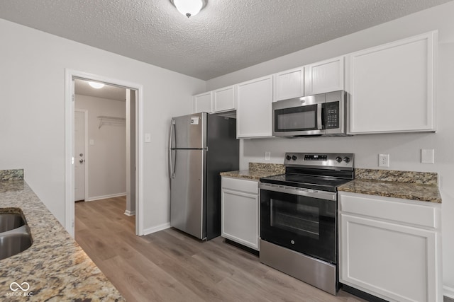 2270 Collins Way, Greenfield, IN 46140 - kitchen with appliances with stainless steel finishes, light wood-style floors, white cabinetry, light stone countertops, and a textured ceiling