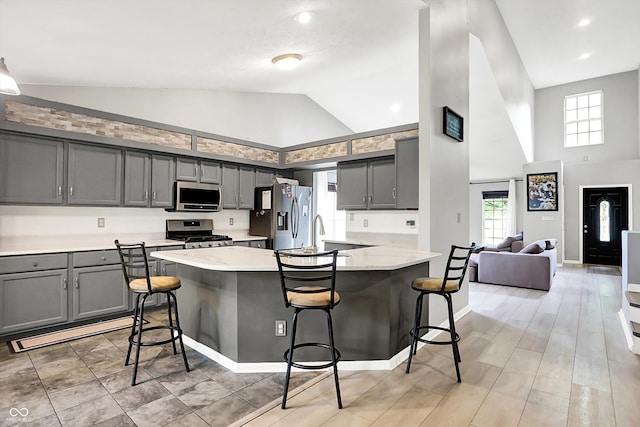 1264 Black Oak Dr, Greenwood, IN 46143 - kitchen with stainless steel appliances, high vaulted ceiling, gray cabinets, a breakfast bar area, and a peninsula
