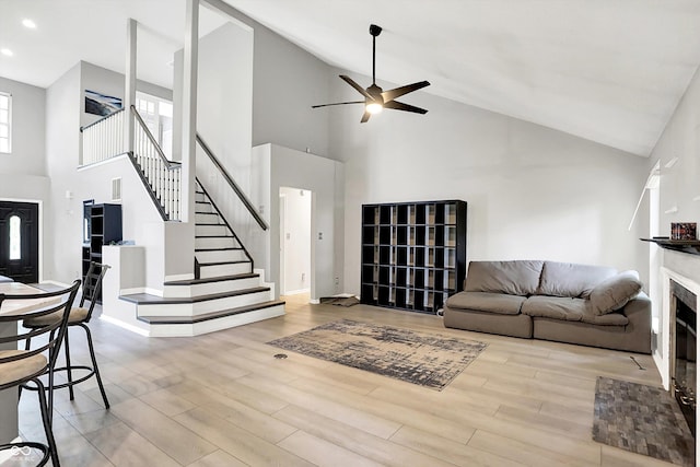 1264 Black Oak Dr, Greenwood, IN 46143 - living area with high vaulted ceiling, a fireplace with flush hearth, stairs, ceiling fan, and wood finished floors