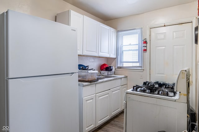 3065 N Colorado Ave, Indianapolis, IN 46218 - kitchen featuring white appliances, white cabinets, wood finished floors, and light countertops
