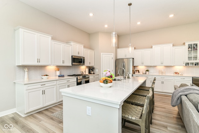 8263 Bryce Blvd, Pendleton, IN 46064 - kitchen with stainless steel appliances, a kitchen bar, tasteful backsplash, white cabinetry, and light wood-type flooring