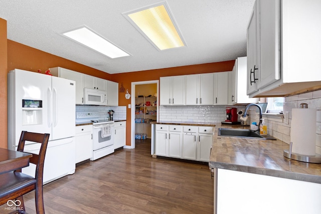 3362 Pavetto Ln, Indianapolis, IN 46203 - kitchen with white appliances, tasteful backsplash, dark wood-style flooring, dark countertops, and white cabinets