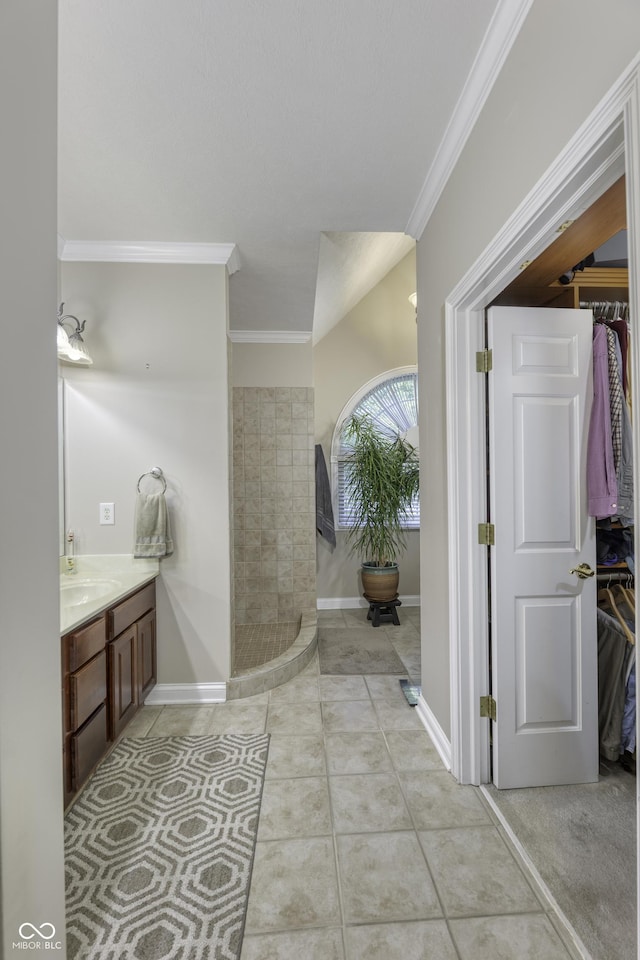 2553 Forest Hills Blvd, Greenwood, IN 46143 - bathroom with ornamental molding, vanity, tiled shower, a walk in closet, and baseboards