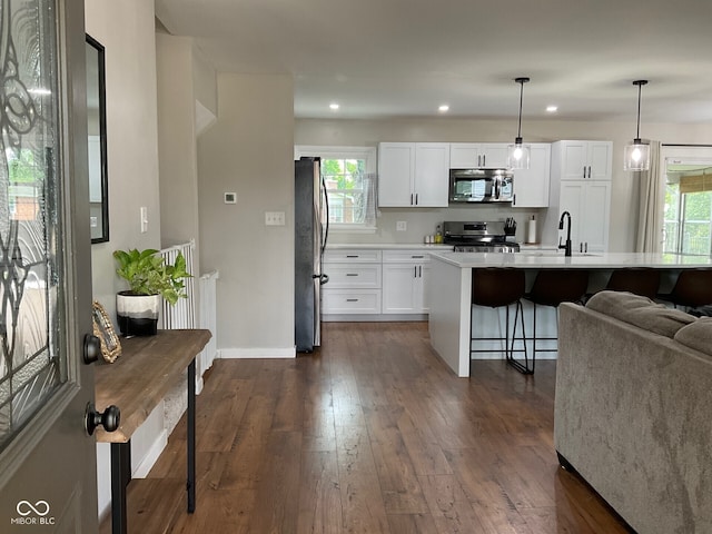 3520 Lantern Ln, Columbus, IN 47203 - kitchen featuring appliances with stainless steel finishes, dark wood-style floors, a breakfast bar area, white cabinets, and light countertops