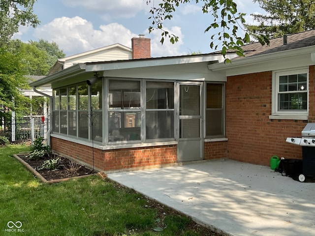 3520 Lantern Ln, Columbus, IN 47203 - back of property with brick siding, a sunroom, a chimney, and a patio area