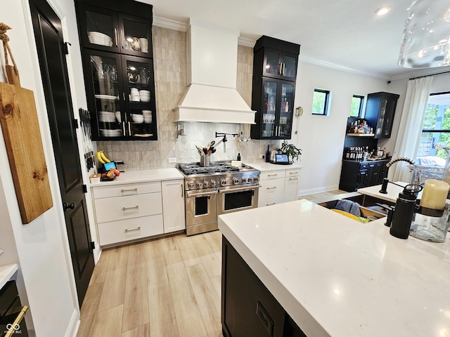 5686 Ellie Ct, Noblesville, IN 46062 - kitchen featuring double oven range, dark cabinetry, premium range hood, light wood finished floors, and crown molding