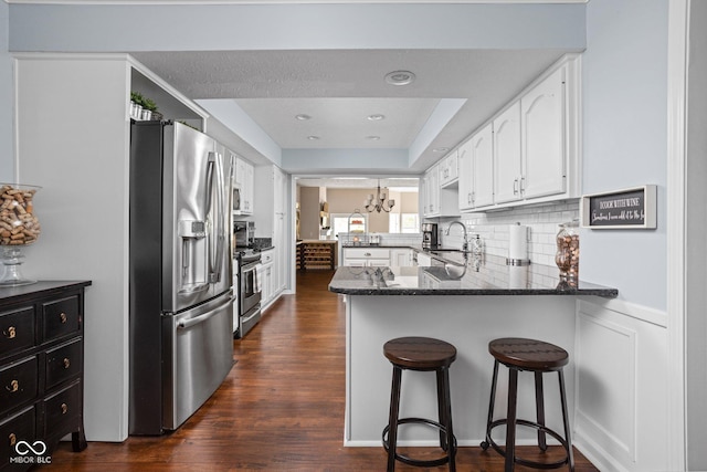 8133 Lower Bay Ln, Indianapolis, IN 46236 - kitchen with appliances with stainless steel finishes, a peninsula, a chandelier, white cabinetry, and backsplash