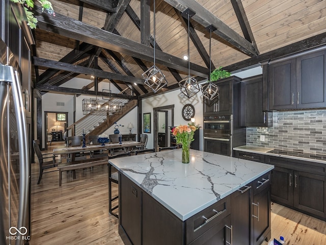 2004 Layton Rd, Anderson, IN 46011 - kitchen with stainless steel appliances, a chandelier, decorative backsplash, a kitchen island, and light stone counters