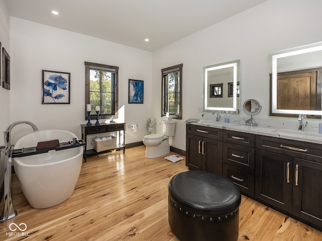 2004 Layton Rd, Anderson, IN 46011 - bathroom with double vanity, a freestanding tub, wood finished floors, toilet, and baseboards
