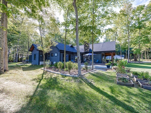 2004 Layton Rd, Anderson, IN 46011 - rear view of property with a garden, a lawn, a chimney, and roof with shingles