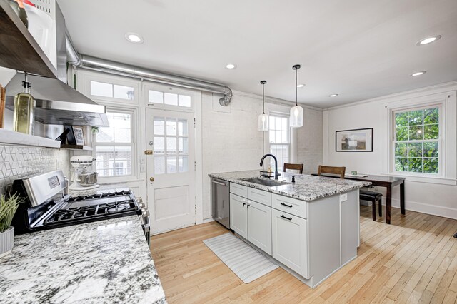 8436 E 56th St, Indianapolis, IN 46216 - kitchen featuring appliances with stainless steel finishes, wall chimney range hood, light wood finished floors, decorative backsplash, and light stone countertops