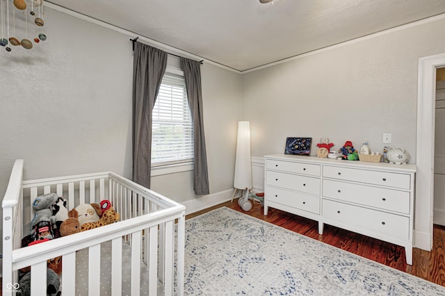 8436 E 56th St, Indianapolis, IN 46216 - bedroom featuring a crib, dark wood-style flooring, and ornamental molding