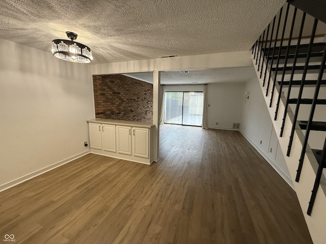 7492 Country Brook Dr, Indianapolis, IN 46260 - unfurnished living room with a textured ceiling, stairs, dark wood finished floors, a chandelier, and baseboards