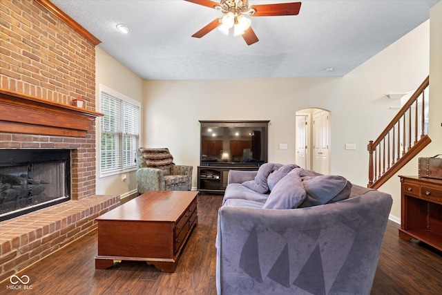 15515 Alameda Pl, Westfield, IN 46074 - living area with stairway, a brick fireplace, a ceiling fan, arched walkways, and dark wood-style floors