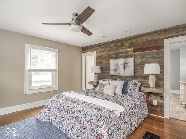 4455 Central Ave, Indianapolis, IN 46205 - bedroom featuring baseboards, wooden walls, an accent wall, wood finished floors, and ceiling fan