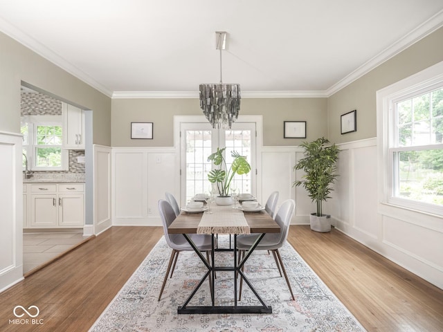 4455 Central Ave, Indianapolis, IN 46205 - dining area featuring a decorative wall, light wood-style floors, a chandelier, crown molding, and wainscoting