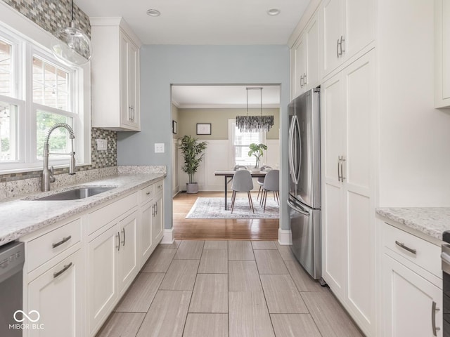 4455 Central Ave, Indianapolis, IN 46205 - kitchen featuring appliances with stainless steel finishes, a sink, white cabinetry, decorative light fixtures, and a chandelier