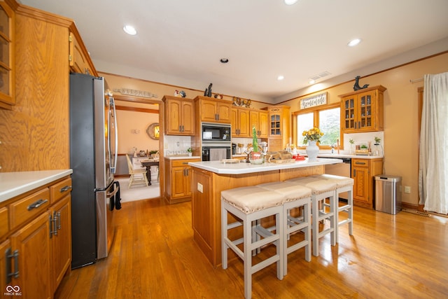 1145 Forest Commons Dr, Avon, IN 46123 - kitchen with black appliances, light countertops, a kitchen island with sink, brown cabinetry, and tasteful backsplash