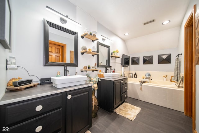 1145 Forest Commons Dr, Avon, IN 46123 - bathroom featuring two vanities, a garden tub, wood finished floors, vaulted ceiling, and recessed lighting