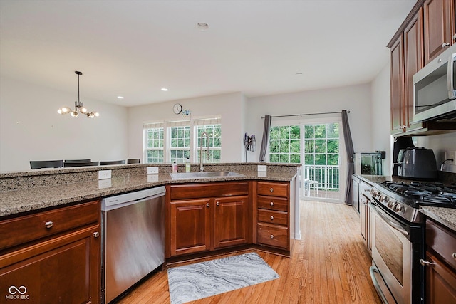 755 Ivy Ln, Carmel, IN 46032 - kitchen featuring appliances with stainless steel finishes, light wood finished floors, a chandelier, dark stone countertops, and decorative light fixtures
