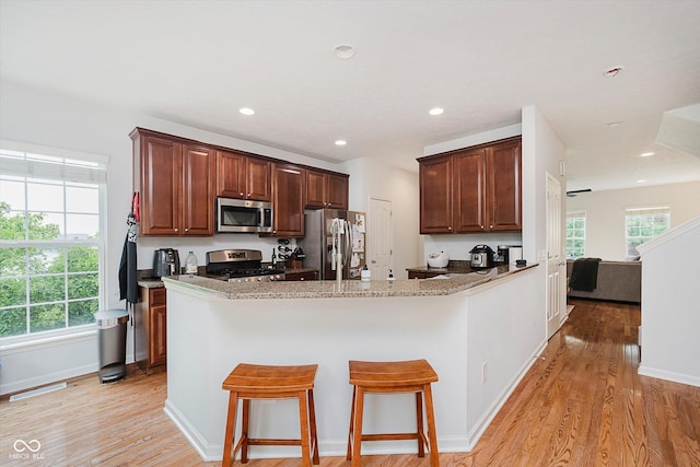 755 Ivy Ln, Carmel, IN 46032 - kitchen featuring appliances with stainless steel finishes, light wood-style flooring, a kitchen bar, a peninsula, and recessed lighting