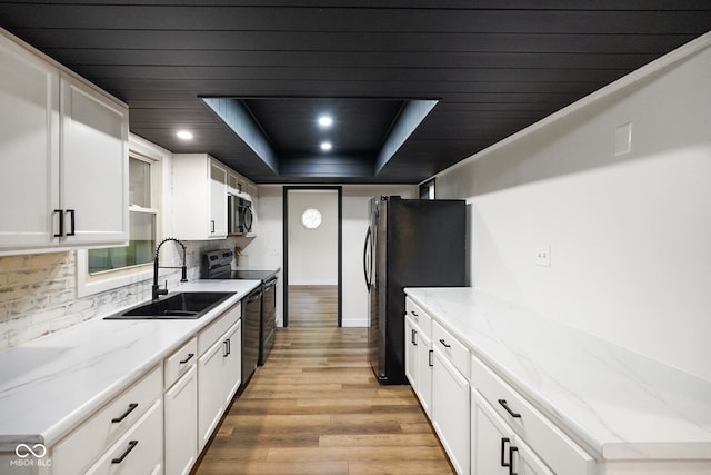 955 Wood Creek Pl, Greenwood, IN 46142 - kitchen featuring a sink, black / electric stove, light wood-style floors, decorative backsplash, and white cabinetry