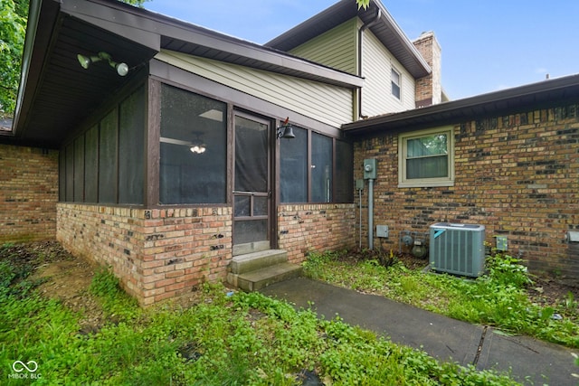 955 Wood Creek Pl, Greenwood, IN 46142 - view of home's exterior with brick siding, central air condition unit, a sunroom, and a chimney