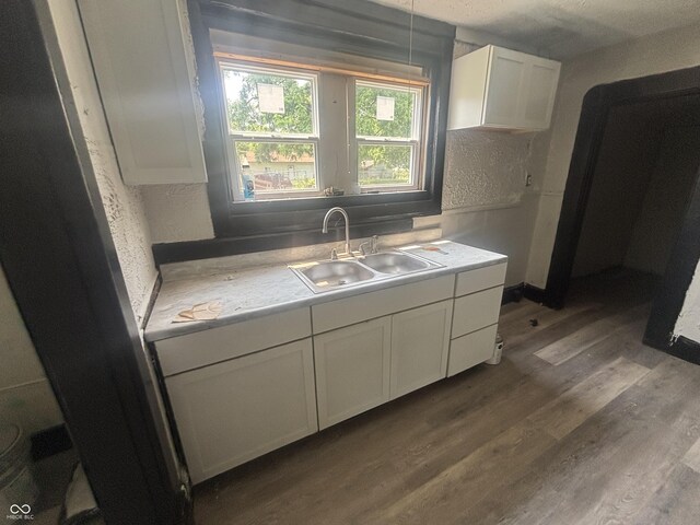 2826 Station St, Indianapolis, IN 46218 - kitchen with a sink, dark wood finished floors, light countertops, white cabinetry, and a textured wall