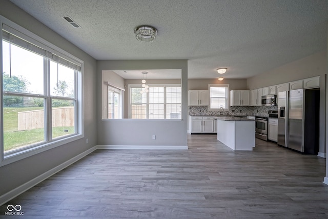 12382 Cool Winds Way, Fishers, IN 46037 - kitchen with appliances with stainless steel finishes, a sink, white cabinets, wood finished floors, and a textured ceiling