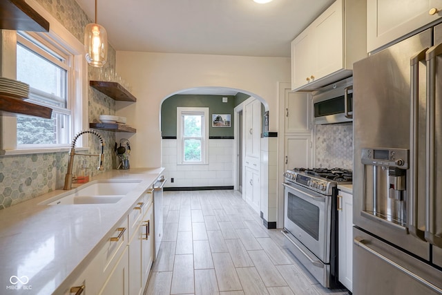 5435 E 10th St, Indianapolis, IN 46219 - kitchen featuring appliances with stainless steel finishes, arched walkways, open shelves, a sink, and white cabinetry
