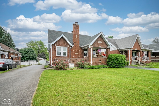 5435 E 10th St, Indianapolis, IN 46219 - view of front of home featuring brick siding, a chimney, a front yard, and a shingled roof