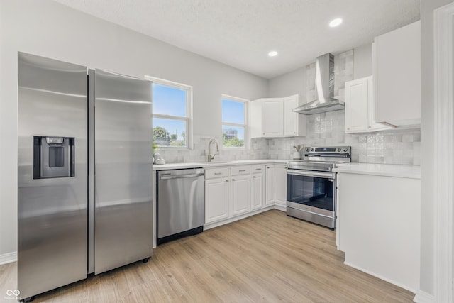 2831 N Talbott St, Indianapolis, IN 46205 - kitchen with appliances with stainless steel finishes, wall chimney range hood, white cabinetry, light wood finished floors, and backsplash