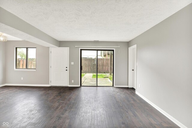 8545 La Corrida Ct, Indianapolis, IN 46227 - empty room with dark wood-type flooring, plenty of natural light, baseboards, and a textured ceiling